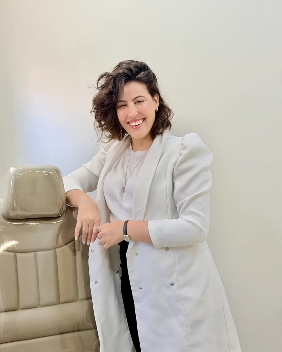 Dra. Dayane Drumond de jaleco, ao lado da cadeira de procedimentos